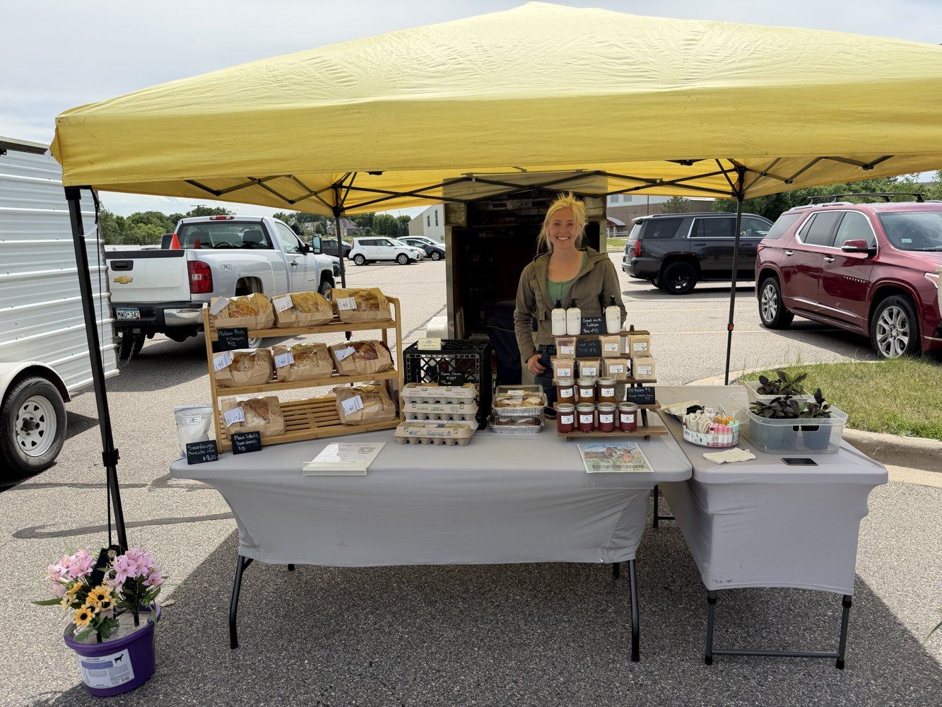 The Fountain Farm farmers market booth with bread, eggs, soaps, jams, and plants