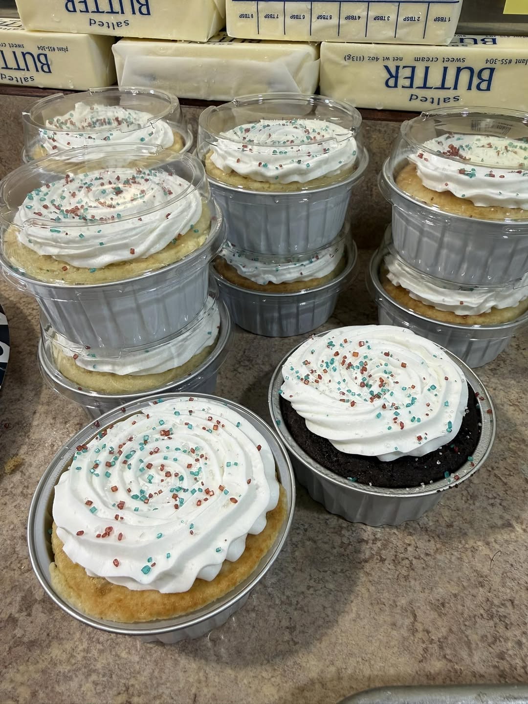 Vanilla and chocolate cake cups topped with white frosting and colorful sprinkles